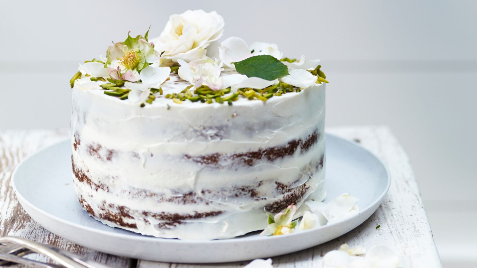 Three-tier pale green wedding cake decorated with sugar roses